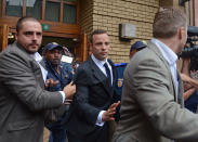 Oscar Pistorius, center, is escorted out of the high court after the first day of his trial in Pretoria, South Africa, Monday, March 3, 2014. Pistorius is charged with murder with premeditation in the shooting death of girlfriend Reeva Steenkamp in the pre-dawn hours of Valentine's Day 2013. (AP Photo)