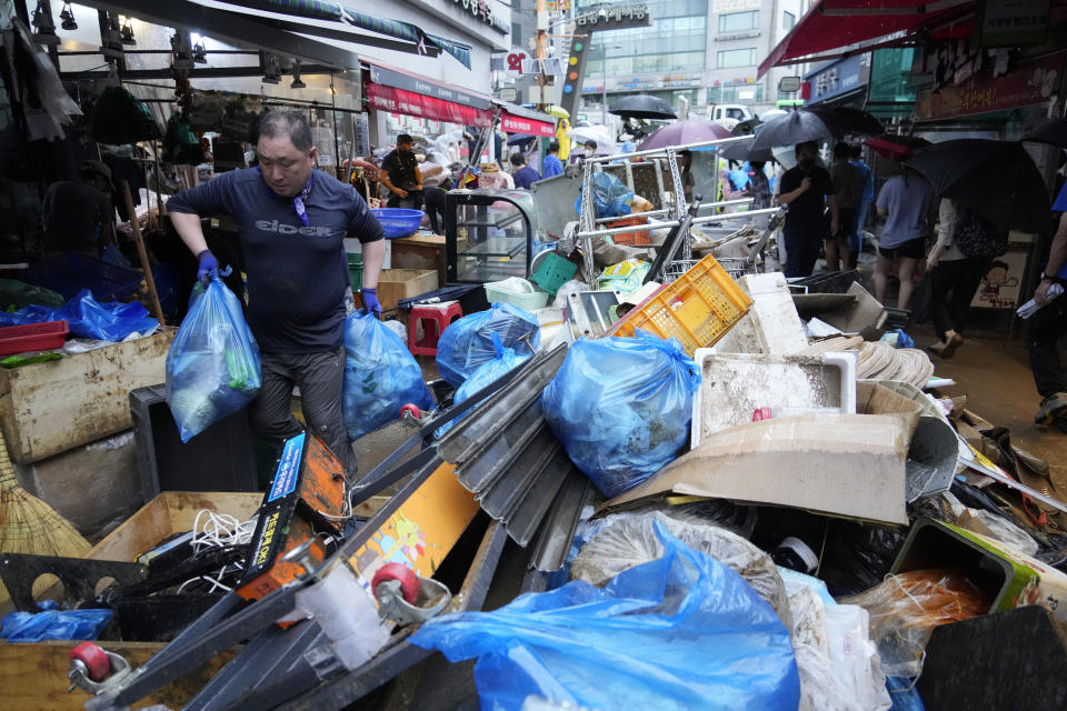 A shop owner carries debris after the water drained from a submerged traditional market following heavy rainfall in Seoul, South Korea, Tuesday, Aug. 9, 2022. Heavy rains drenched South Korea's capital region, turning the streets of Seoul's affluent Gangnam district into a river, leaving submerged vehicles and overwhelming public transport systems. (AP Photo/Ahn Young-joon)