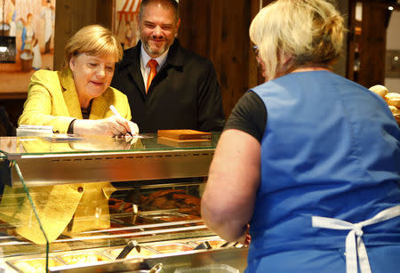 German Chancellor Angela Merkel signs an autograph for a woman inside a butcher shop during the final Christian Democratic Union (CDU) party campaign in Stralsund, Germany, September 23, 2017. REUTERS/Axel Schmidt