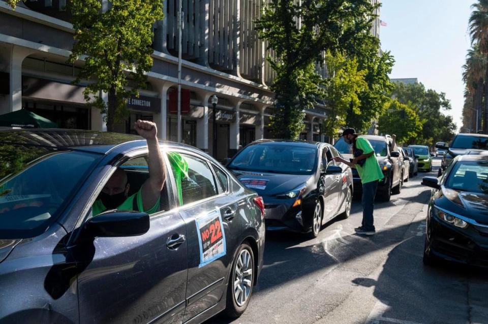 Danny Raviart holds a fist in the air at a car rally against Proposition 22 at the state Capitol in Sacramento on Thursday, Oct. 15, 2020. The initiative would exempt app-based transportation and delivery services from a new state labor law, allowing them to continue to employ drivers as independent contractors.