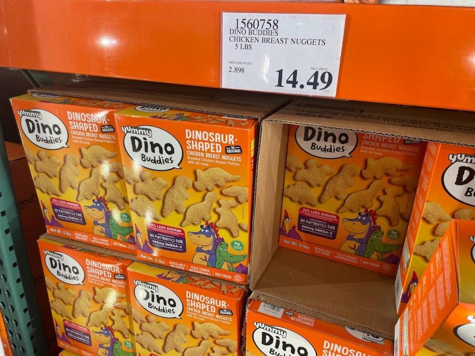 Large boxes of dinosaur-shaped chicken nuggets at Costco, with a price tag that reads $14.49.