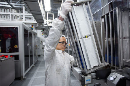 Marie Grace Sheppard, a production operator, loads a cart of cells into a machine at the Solar World solar panel factory in Hillsboro, Oregon, U.S., January 15, 2018. Picture taken January 15, 2018. REUTERS/Natalie Behring