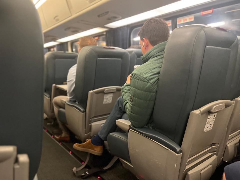 A man in a green jacket sitting on the Amtrak.