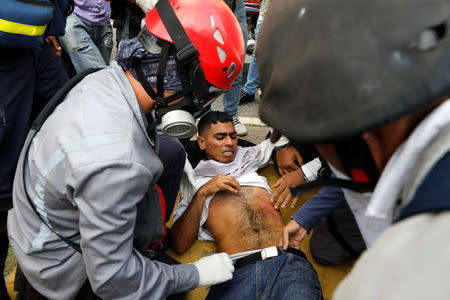 An opposition supporter is helped during a clash with security forces in a rally against Venezuela's President Nicolas Maduro in Caracas. REUTERS/Carlos Garcia Rawlins