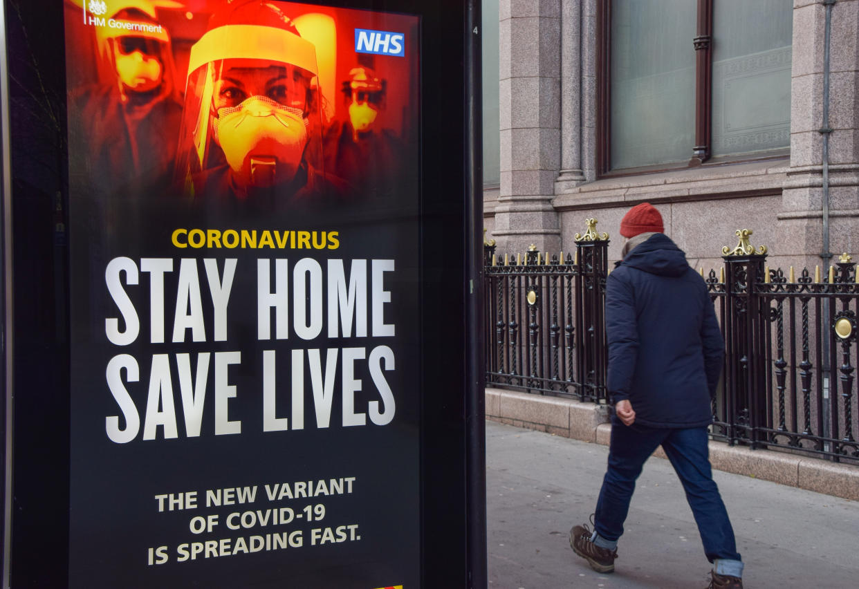 LONDON, UNITED KINGDOM - 2021/01/09: A man walks past a 'Stay Home Save Lives' sign in Central London. The posters are part of a government campaign to get people to comply with lockdown rules as Coronavirus cases continue to rise. (Photo by Vuk Valcic/SOPA Images/LightRocket via Getty Images)