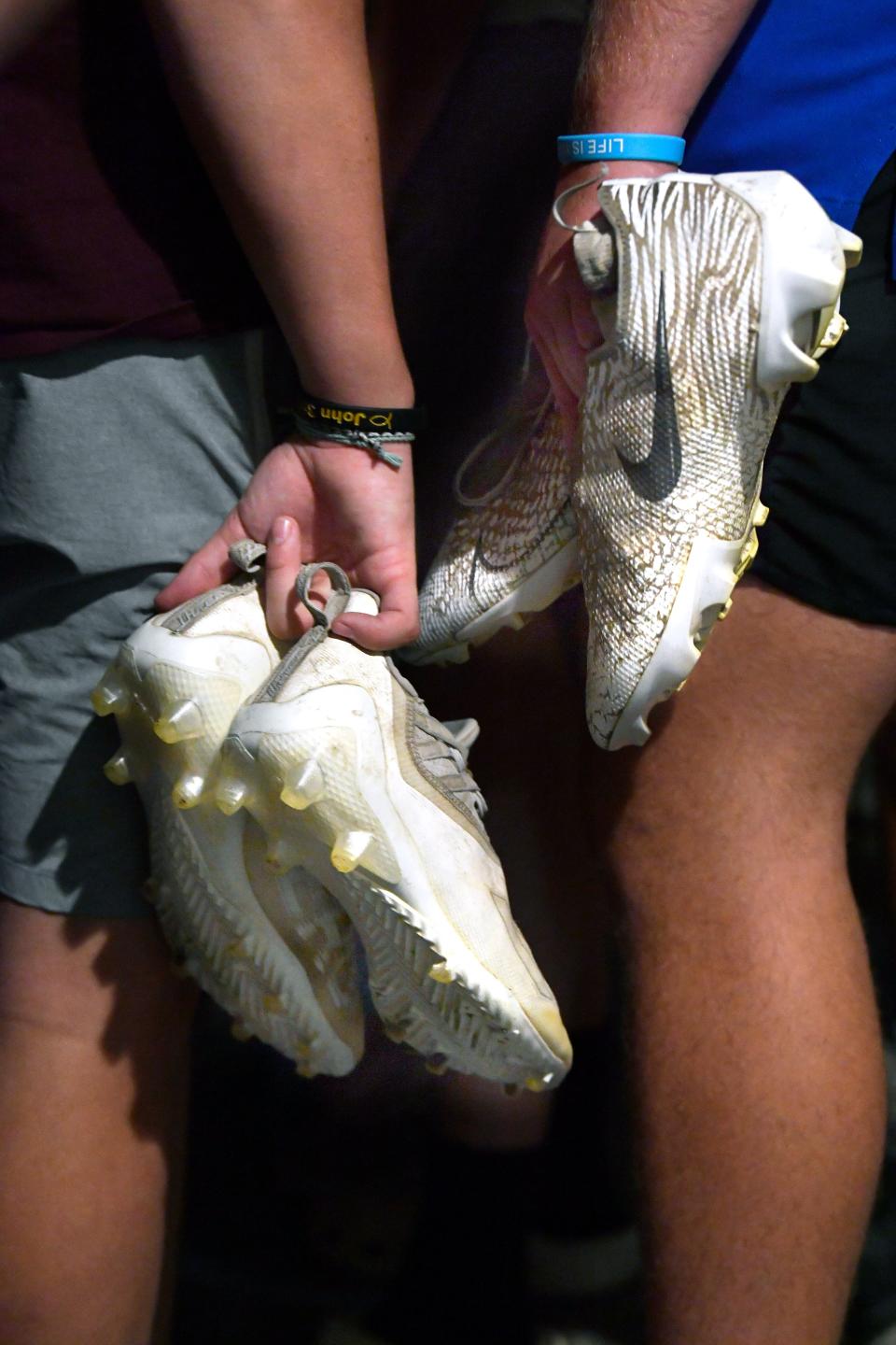 Football players hold their cleats by their sides as they wait to enter the locker room minutes before midnight at Comanche High School Sunday. The team kicked off its season with a first practice at midnight.