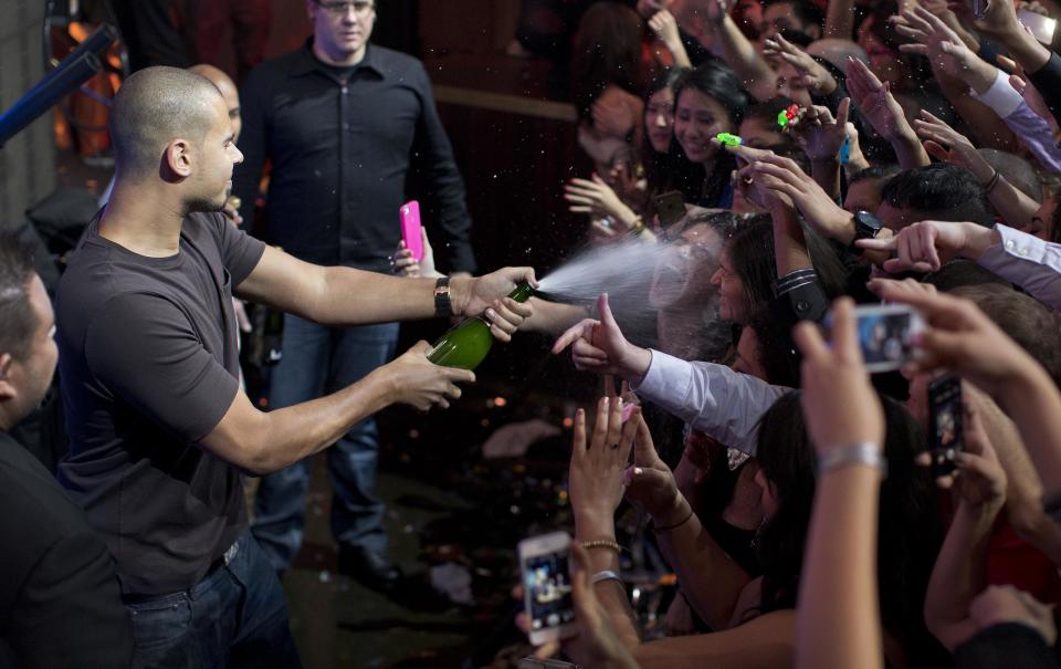 DJ Afrojack, left, sprays a crowd of revelers with champagne while performing at the XS nightclub in Las Vegas on Sunday, Jan. 20, 2013. The globe-trotting Dutch 25-year-old said he has come to consider the Strip his home because it's the one place he believes is as dance-music-focused as he is. (AP Photo/Julie Jacobson)