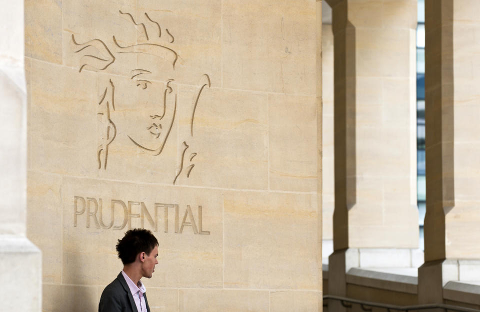 A pedestrian pauses by the Prudential Plc company logo. Photo: Frantzesco Kangaris/Bloomberg  