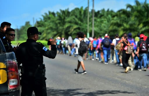 Guatemalan policemen film Honduran migrants heading north after they broke through the country's southern border with Honduras