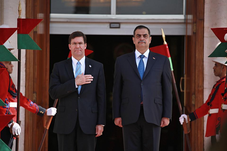 Iraqi Defense Minister Najah al-Shammari, right, and U.S. Defense Secretary Mark Esper, left, stand for their country's national anthems during a welcome ceremony at the Ministry of Defense, Baghdad, Iraq, Wednesday, Oct. 23, 2019. Esper has arrived in Baghdad on a visit aimed at working out details about the future of American troops that are withdrawing from Syria to neighboring Iraq. (AP Photo/Hadi Mizban)