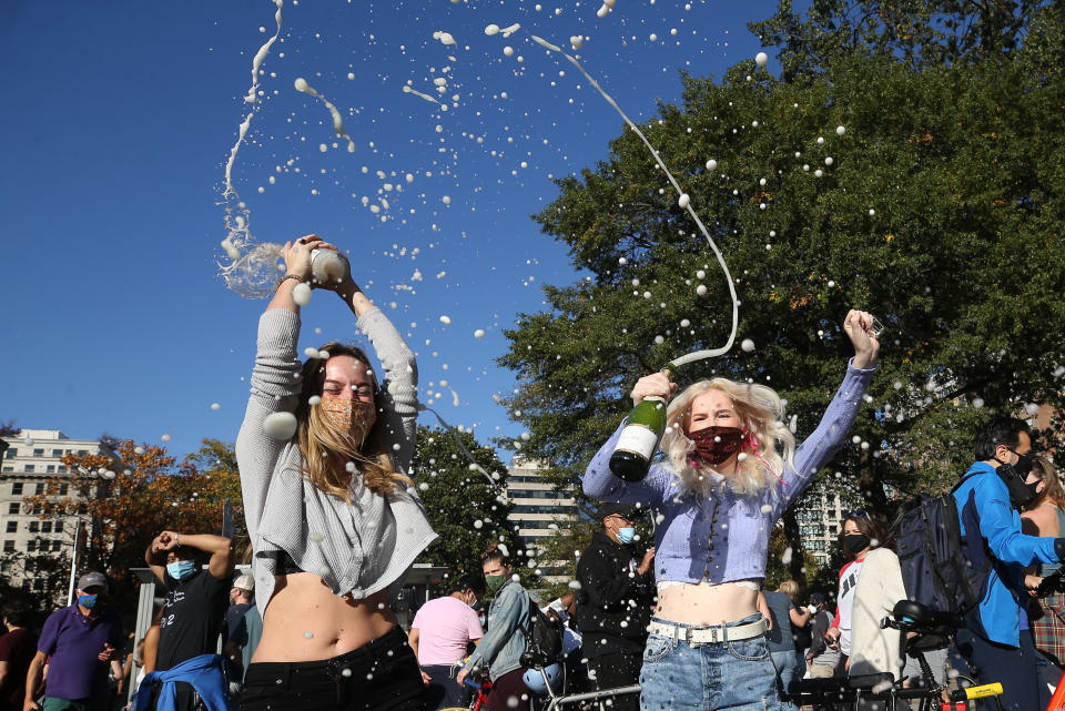 Two women in Washington spray sparkling wine in a street as they celebrate after the media announcement that Democratic Party nominee Joe Biden has won. Source: Getty