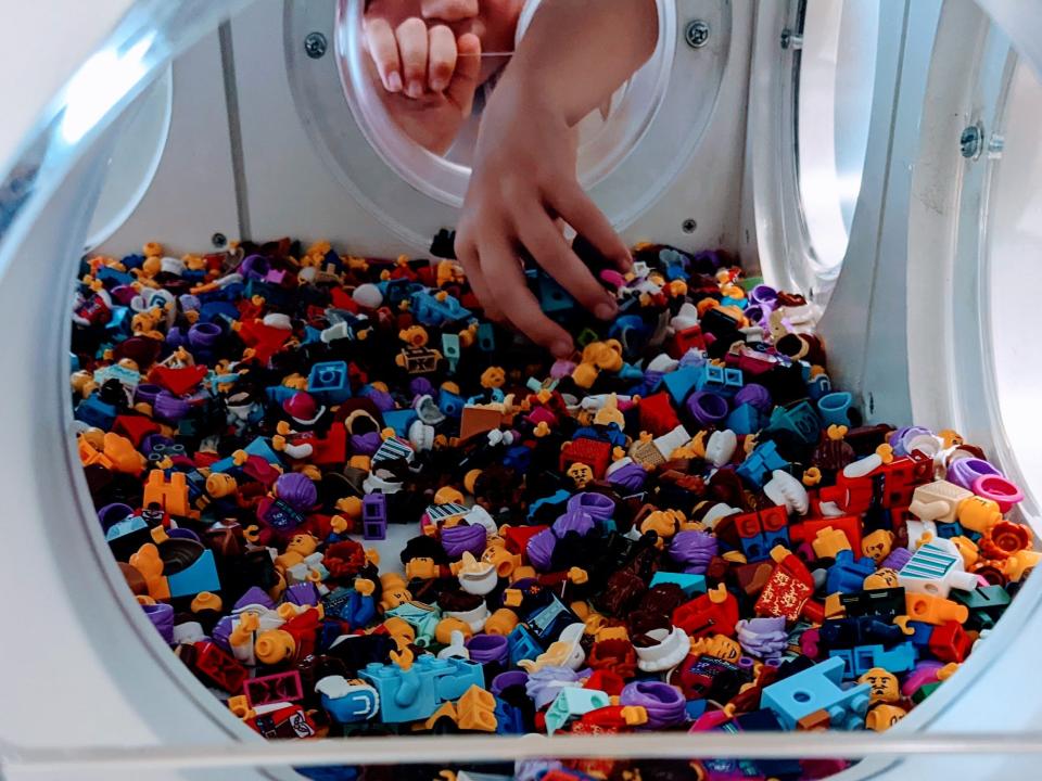 hand reaching into a container full of little lego figurines at the lego store at disney springs