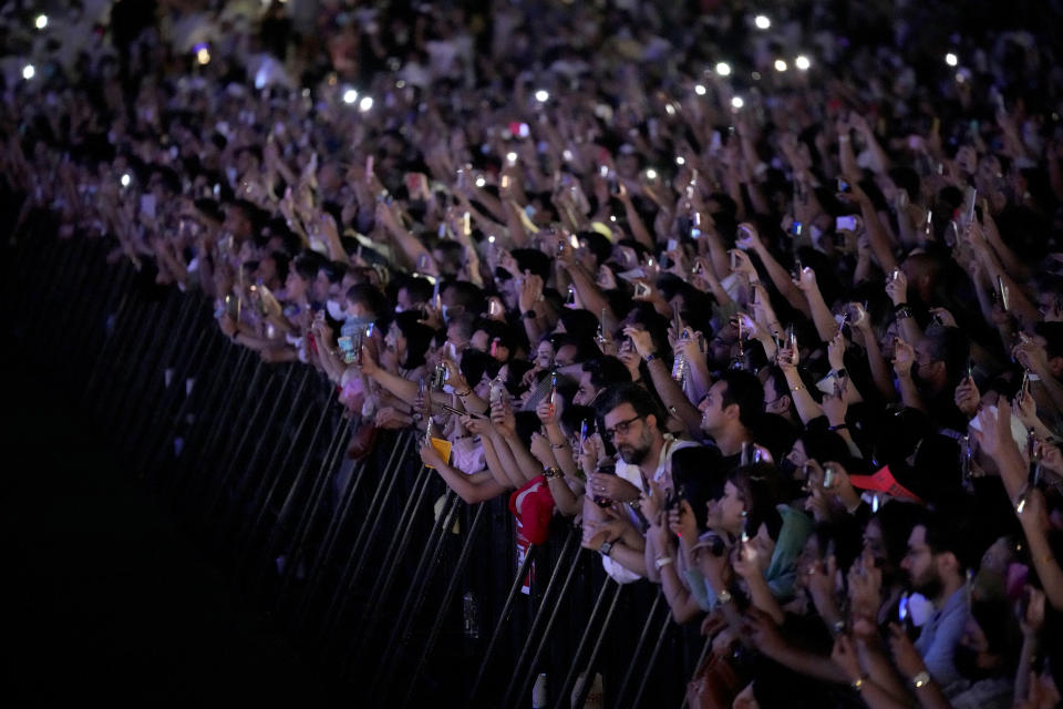 Fans enjoy the Iranian pop star Googoosh performance at the Dubai Expo 2020, in Dubai, United Arab Emirates, Thursday, March 17, 2022. Iranian pop diva and national icon Googoosh delivered old hits and songs from her new album to a packed stadium on Thursday in Dubai — just across the Persian Gulf from her home that had banned her from singing for 21 years and where authorities to this day continue to protest her performances. (AP Photo/Ebrahim Noroozi)