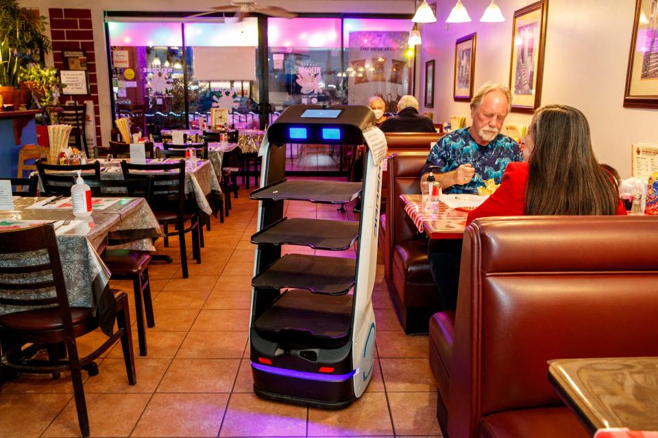 Robot Rosi returns to the kitchen after delivering food to Kevin and Maria Fenton inside Haus of Pizza in Palm Desert, Calif., on Jan. 10, 2022. After having difficulty finding workers despite raising wages, Haus of Pizza took the innovative step of leasing a serving robot. 