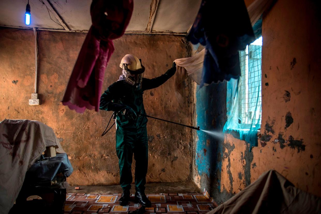 A worker of Anglogold Ashanti Malaria Ltd sprays the walls of a house with insecticide against mosquitos