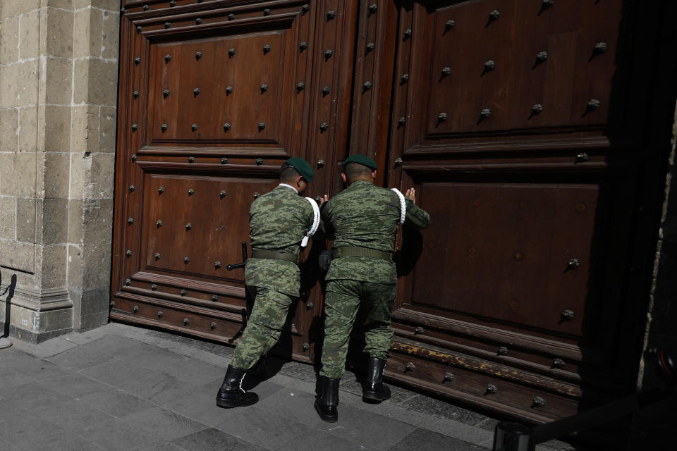 Military police push open heavy wooden doors to allow a car to exit, as Mexican officials arrive for a private meeting between U.S. Attorney General William Barr and Mexico's President Andres Manuel Lopez Obrador, in Mexico City, Thursday, Dec. 5, 2019. (AP Photo/Rebecca Blackwell)