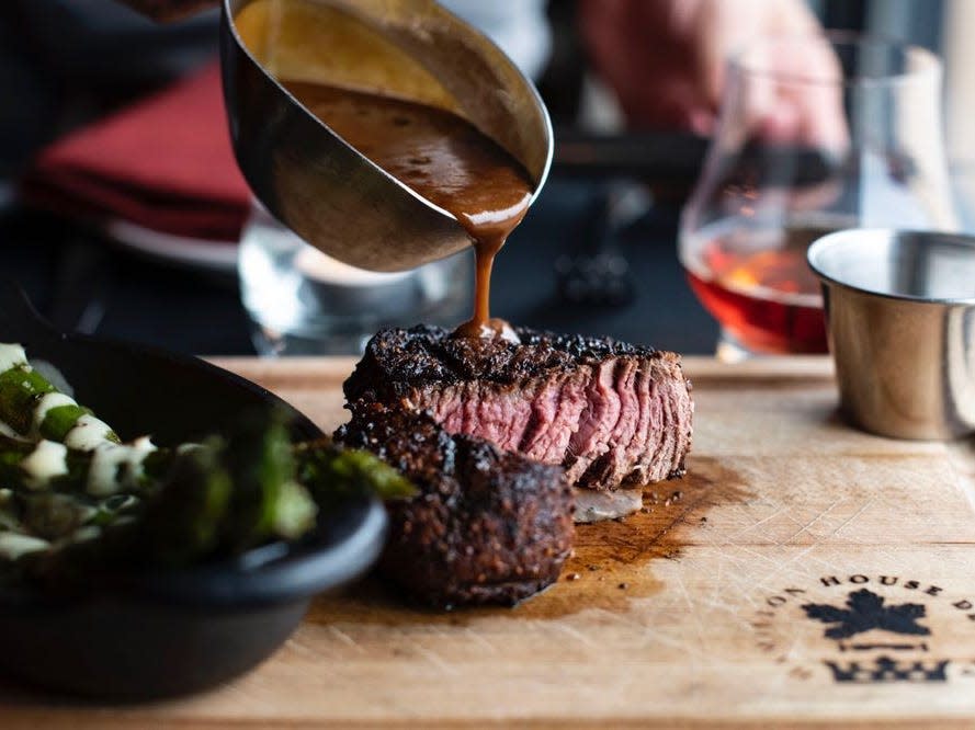 Sauce being poured on steak at Hamilton's Urban Steakhouse and Bourbon Bar