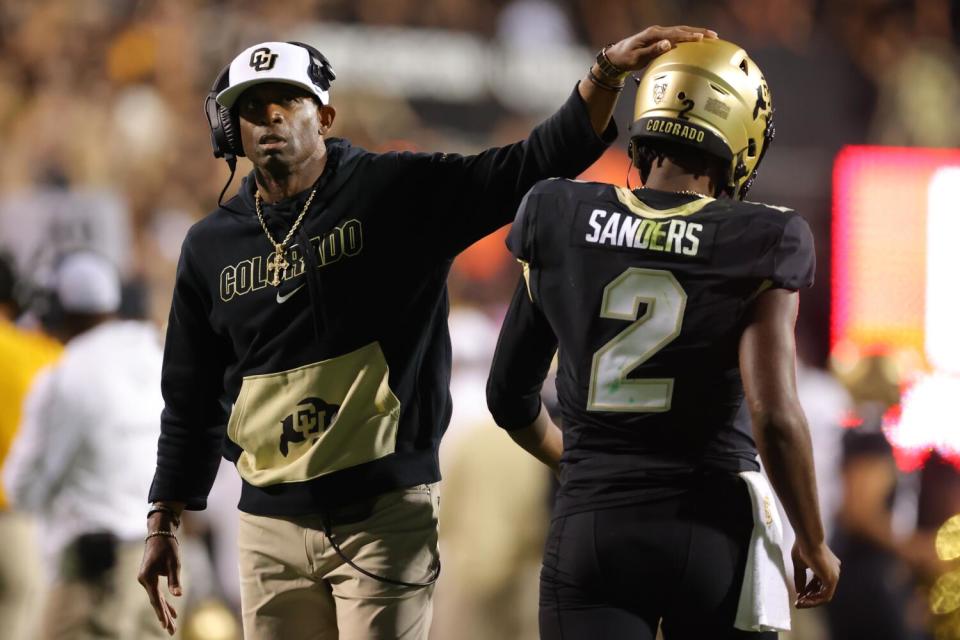 Colorado coach Deion Sanders taps his son, quarterback Shedeur Sanders, on the helmet after he led a touchdown drive