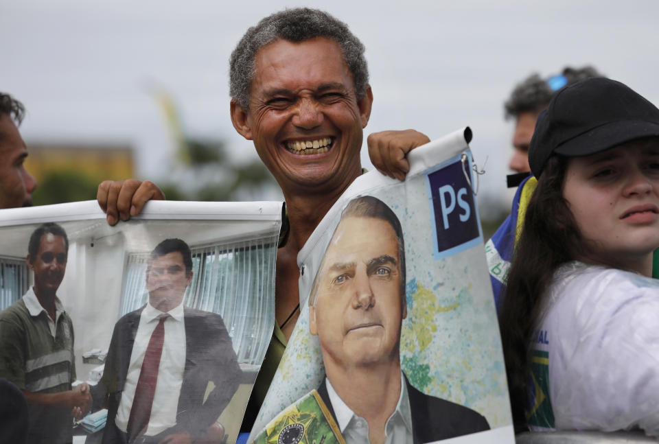 A supporter holds a photo of Brazil's former army captain Jair Bolsonaro before the swearing-in ceremony in front of the Planalto palace in Brasilia, Brail, Tuesday Jan. 1, 2019. Once an outsider mocked by fellow lawmakers for his far-right positions, constant use of expletives and even casual dressing, Bolsonaro is taking office as Brazil's president Tuesday. (AP Photo/Silvia Izquierdo)