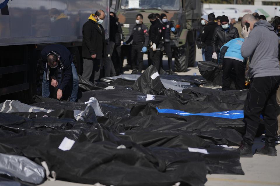 People stand over the bodies of earthquake victims outside a hospital in Antakya, southeastern Turkey, Thursday, Feb. 9, 2023. Thousands who lost their homes in a catastrophic earthquake huddled around campfires and clamored for food and water in the bitter cold, three days after the temblor and series of aftershocks hit Turkey and Syria. (AP Photo/Khalil Hamra)