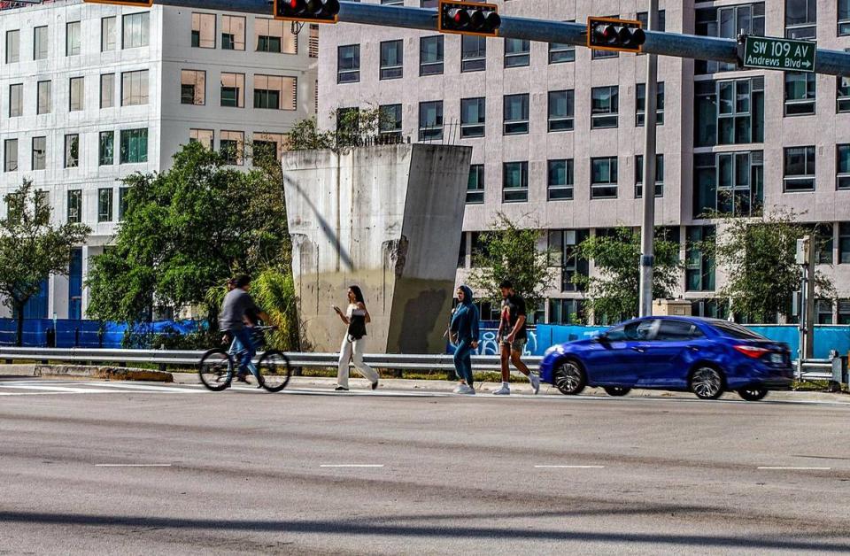 Students cross Southwest Eighth Street in front of a support pylon left in place after a pedestrian bridge collapsed while under construction across the busy road in March 2018. The column, on the north side of the road at 109th Avenue, will be demolished once construction starts in early 2024 on a proposed new bridge linking Sweetwater’s residential University City district, seen in the background, and FIU’s main campus.