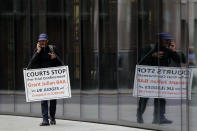 A protestor on a mobile phone stands opposite the Central Criminal Court, the Old Bailey, in London, Monday, Sept. 21, 2020, as the Julian Assange extradition hearing to the US continues. (AP Photo/Frank Augstein)