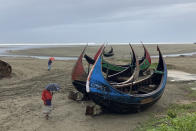 Fisherman walk near the boats anchored at the coast in Cox's Bazar district, Bangladesh, Sunday, May 14, 2023. Bangladesh and Myanmar are bracing as an extremely severe cyclone starts to hit their coastal areas, and authorities urged thousands of people in both countries to seek shelter. (AP Photo/Al-emrun Garjon)