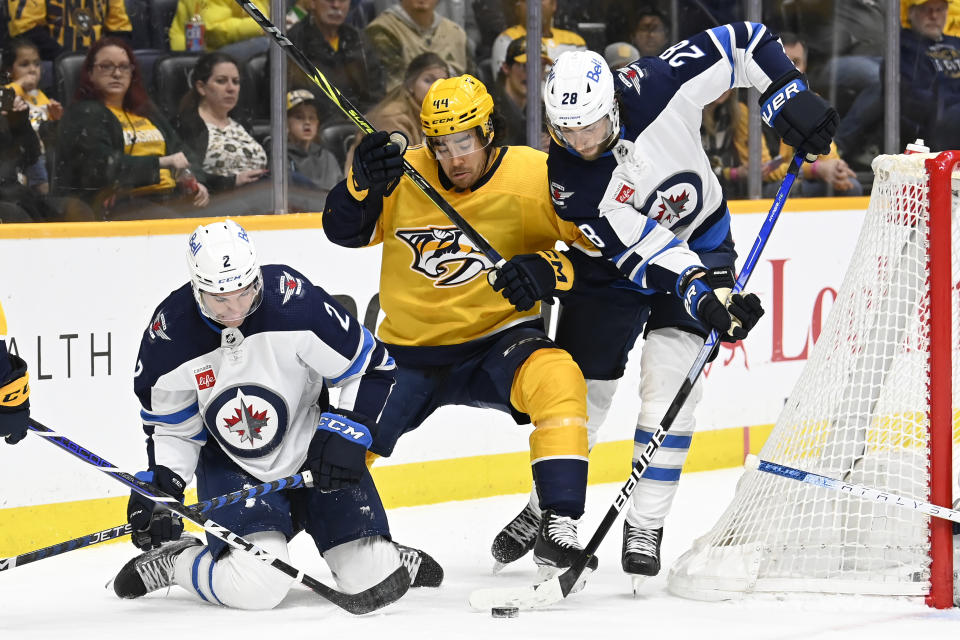 Nashville Predators left wing Kiefer Sherwood (44) battles Winnipeg Jets defenseman Dylan DeMelo (2) and center Kevin Stenlund (28) for the puck during the second period of an NHL hockey game Saturday, March 18, 2023, in Nashville, Tenn. (AP Photo/Mark Zaleski)