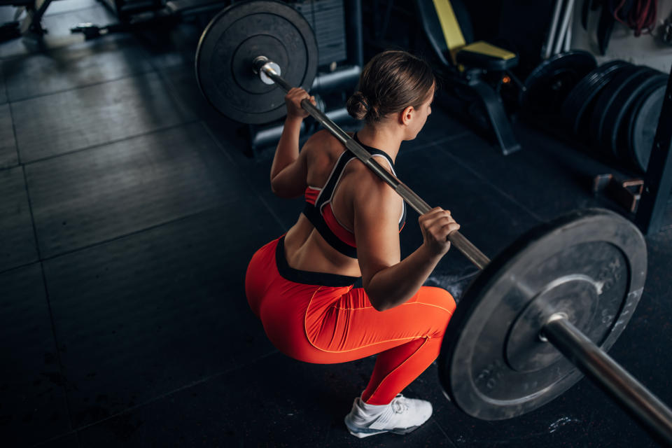 One woman, fit young woman training with weights alone in gym.