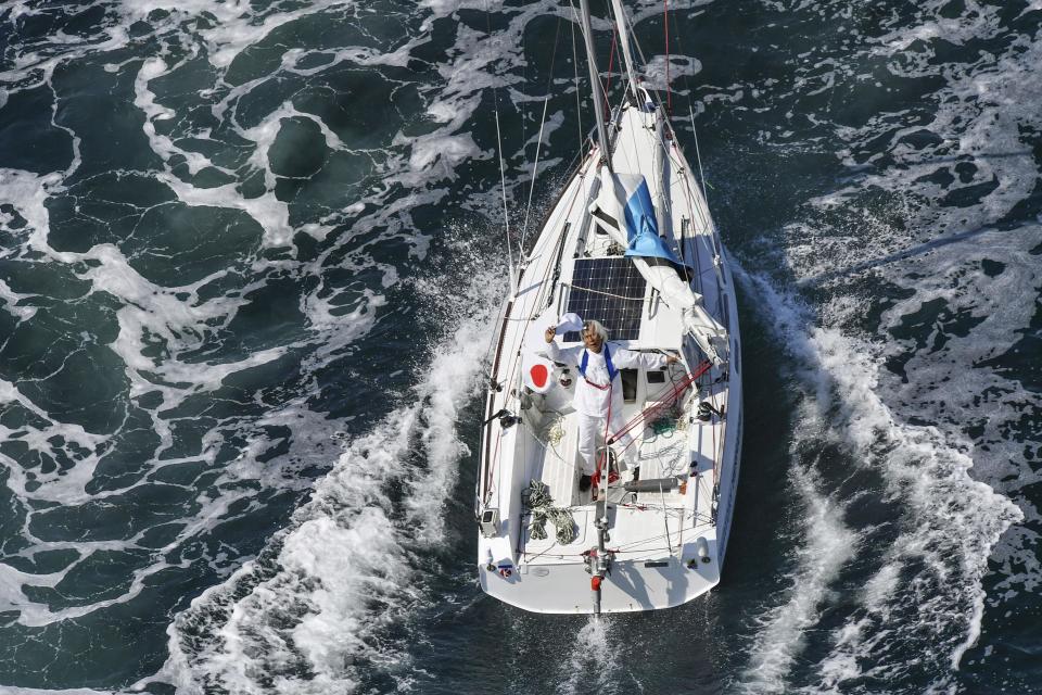 Japan's Kenichi Horie waves on his sailing boat after his trans-Pacific voyage, at Osaka Bay, western Japan, Saturday, June 4, 2022. The 83-year-old Japanese adventurer returned home Saturday after successfully completing his solo, nonstop voyage across the Pacific, becoming the oldest person to reach the milestone.(Kyodo News via AP)