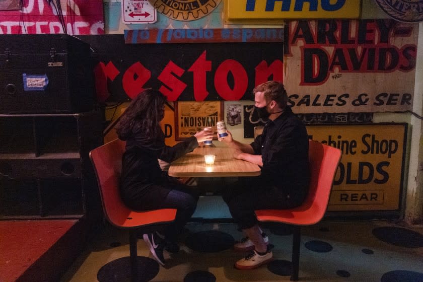 LOS ANGELES, CA - APRIL 02: Jasmine Aguilar, left, and Adam Ziegenhals, right, both of Echo Park, stop in for a beer inside the empty Ham & Eggs Tavern on Friday, April 2, 2021 in Los Angeles, CA. They are the only customers. During the on going global pandemic Los Angeles is preparing to allow bars that don't serve food to re open. (Francine Orr / Los Angeles Times)