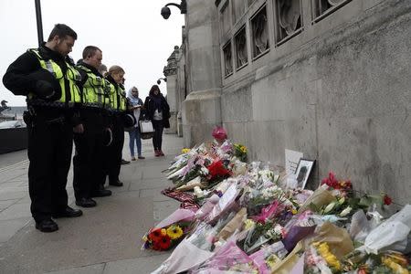 Police officers and civilians look at floral tributes near Westminster Bridge following a recent attack in Westminster, in London, Britain March 24, 2017. REUTERS/Darren Staples