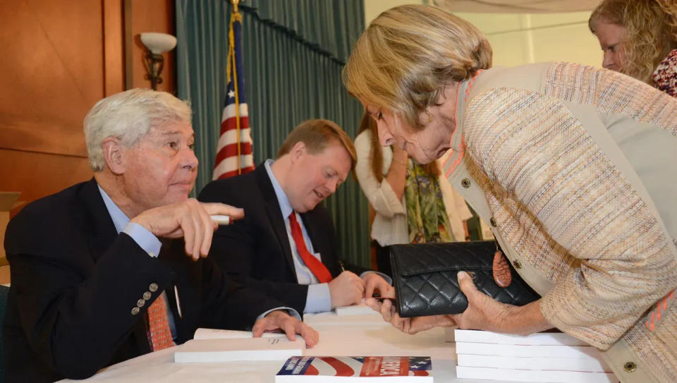 Former Florida Gov. and U.S. Sen. Bob Graham autographs one of his books at a League of Women Voters of Space Coast lunch in Cape Canaveral. At right is co-author Chris Hand.