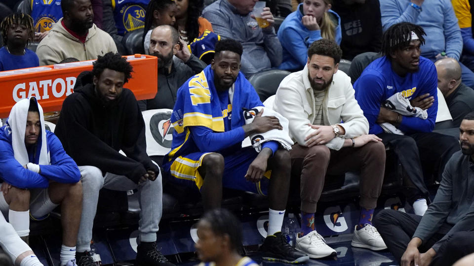 Golden State Warriors forward Andrew Wiggins, second left, and guard Klay Thompson, second right, both in street clothes because they did not play, sit on the bench in the second half of an NBA basketball game against the New Orleans Pelicans in New Orleans, Monday, Nov. 21, 2022. The Pelicans won 128-83. (AP Photo/Gerald Herbert)