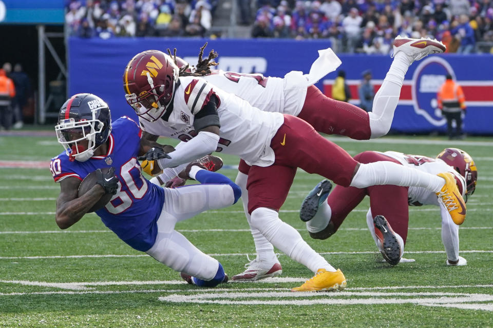 New York Giants' Richie James, left, is tackled by Washington Commanders' defenders during the first half of an NFL football game, Sunday, Dec. 4, 2022, in East Rutherford, N.J. (AP Photo/John Minchillo)