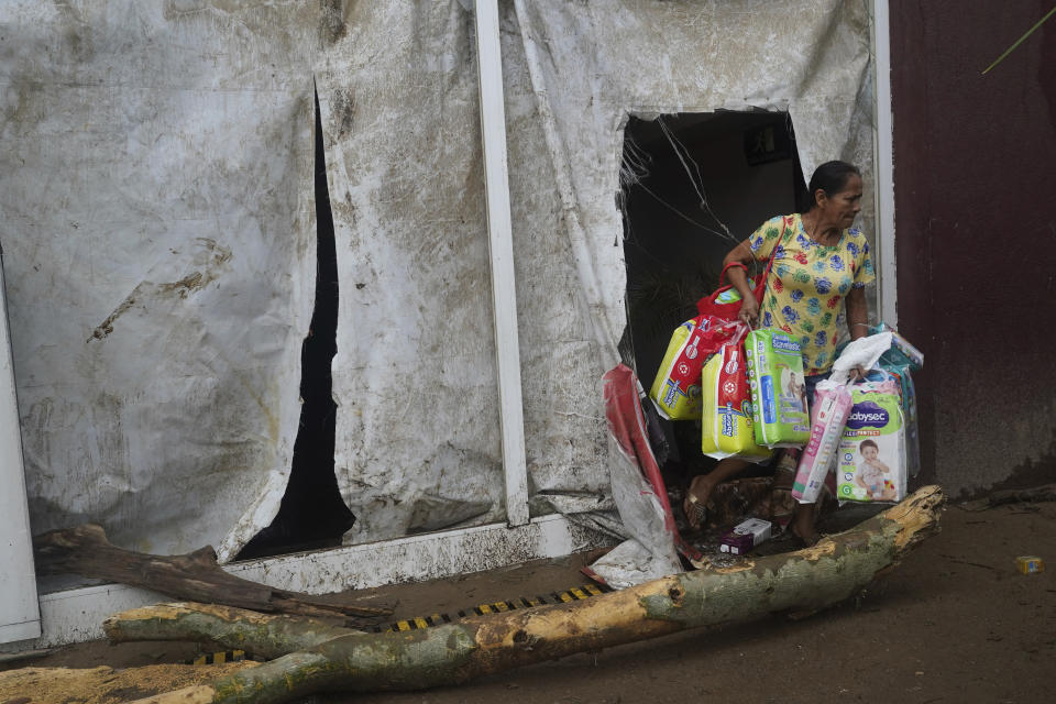 A woman loots a supermarket after Hurricane Otis ripped through Acapulco, Mexico, Wednesday, Oct. 25, 2023. Hurricane Otis ripped through Mexico's southern Pacific coast as a powerful Category 5 storm, unleashing massive flooding, ravaging roads and leaving large swaths of the southwestern state of Guerrero without power or cellphone service. (AP Photo/Marco Ugarte)