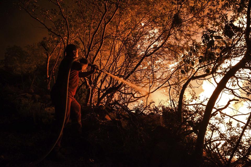 A firefighter battles with fire in Kirli village near the town of Manavgat, in Antalya province, Turkey early Friday July 30, 2021. The fire that continued all night could not be brought under control and people living in the village started to evacuate. Wildfires are common in Turkey's Mediterranean and Aegean regions during the arid summer months, although some previous forest fires have been blamed on arson.(AP Photo)