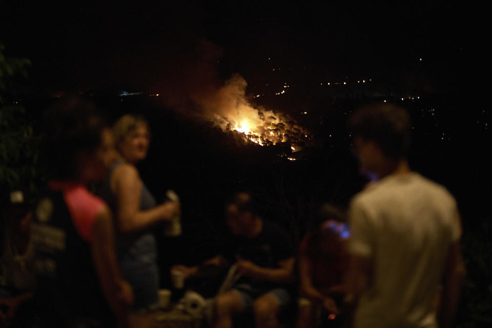 Trees burn as flames and smoke engulf the top of a hill in a forest fire in Artazu, northern Spain in the early hours of Sunday, June 19, 2022. Firefighters in Spain are struggling to contain wildfires in several parts of the country suffering an unusual heat wave for this time of the year. (AP Photo/Miguel Oses)