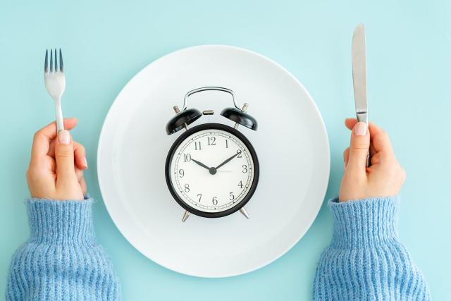 Female hands with fishing rod and alarm clock on color background