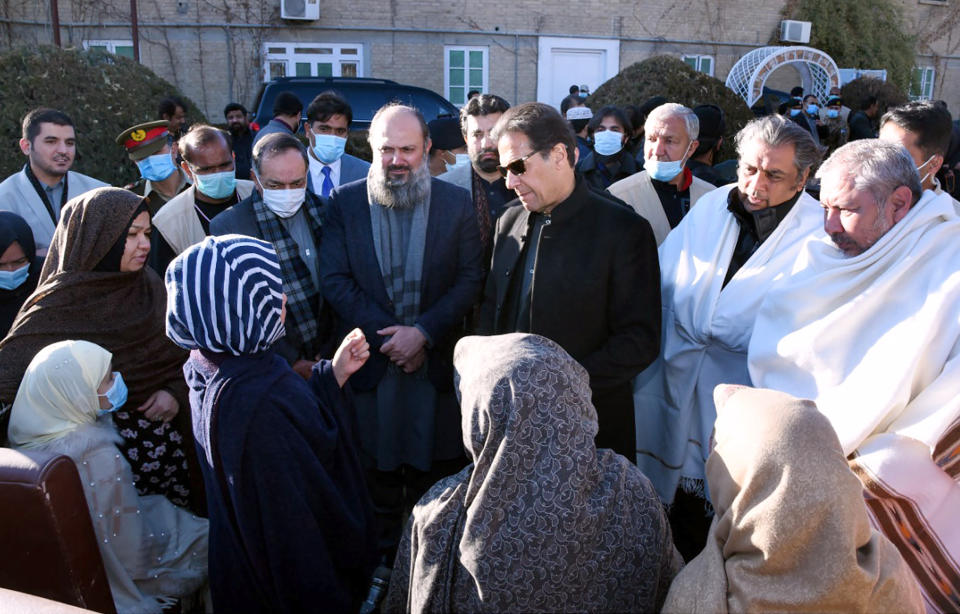 In this photo provided by Press Information Department, Pakistani Prime Minister Imran Khan, center, and other officials listen to families of the Shiite Hazara community's coal mine workers, who were killed by gunmen near the Machh coal field, at a meeting, in Quetta, Pakistan, Saturday, Jan. 9, 2021. Hundreds of Pakistani Shiites gathered to bury 11 coal miners from the minority Hazara community who were killed by the Islamic State group, ending over a week of protests that sought to highlight the minority community's plight. (Press Information Department via AP)