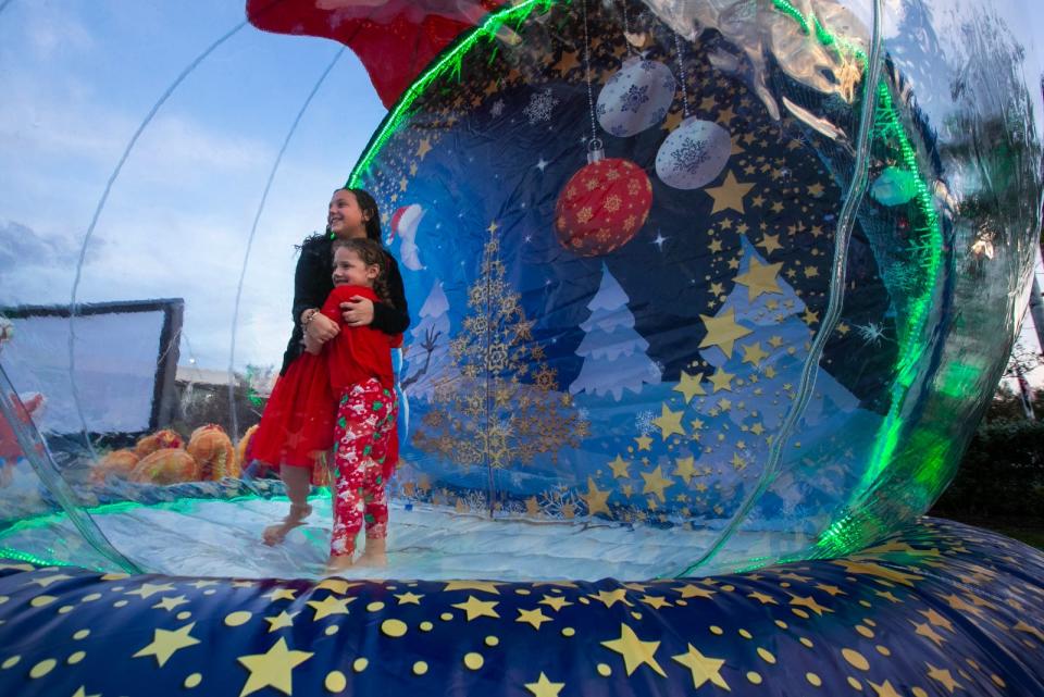 Sisters Emmaline Beaumont, 10, and 
Genevieve Beaumont, 5, of Cape Coral, embrace while having their picture taken inside a large inflatable snow globe. The city of Cape Coral hosted its 3rd Annual Holiday Tree and Menorah Lighting ceremony on the lawn at City Hall on Thursday, Nov. 30, 2023. The Christmas tree, installed by city employees, was 50 feet tall and included colorful ornaments. 
The family-friendly event included a musical performance by student choirs from both Oasis Elementary North and South. A visit from Santa Claus also gave visitors an opportunity to have pictures taken with him.