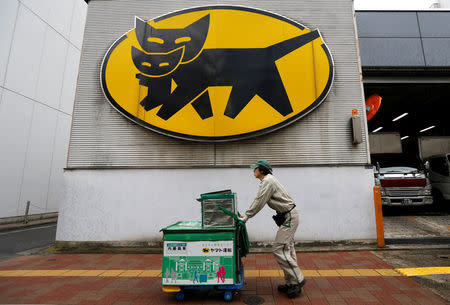 A deliverer of Yamato Transport Co is seen under the company's logo at a business district in Tokyo, Japan, February 9, 2017. REUTERS/Toru Hanai