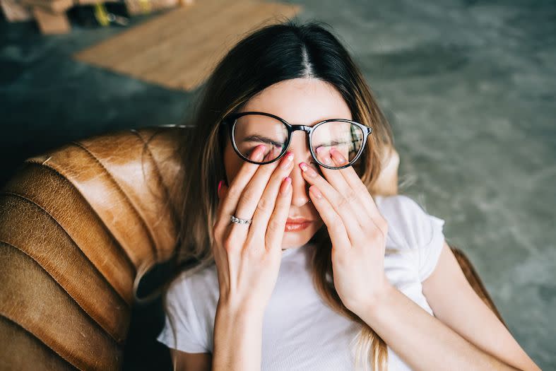 young woman rubs her eyes and looks stressed