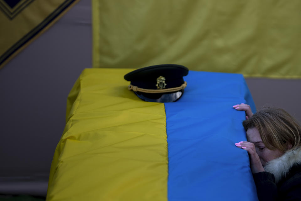 FILE - Svitlana Havryliuk kneels next to the coffin of her husband, Serhii, 48, at his funeral in Tarasivka village, near Kyiv, Ukraine, on Feb. 15, 2023. Havryliuk, an officer of the Azov Assault Brigade, died while defending the Azovstal steel plant in Mariupol on April 12, 2022. He was finally buried after DNA tests confirmed his identity. (AP Photo/Emilio Morenatti, File)