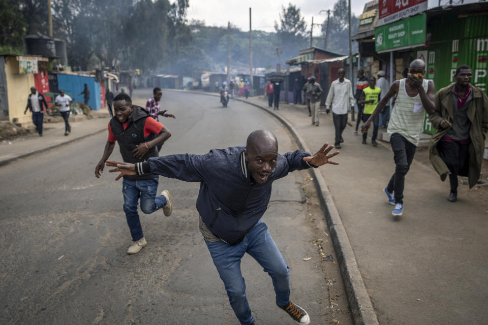 Protesters run from tear gas fired by police in the Kibera slum of Nairobi, Kenya Monday, March 20, 2023. Hundreds of opposition supporters have taken to the streets of the Kenyan capital over the result of the last election and the rising cost of living, in protests organized by the opposition demanding that the president resigns from office. (AP Photo/Ben Curtis)