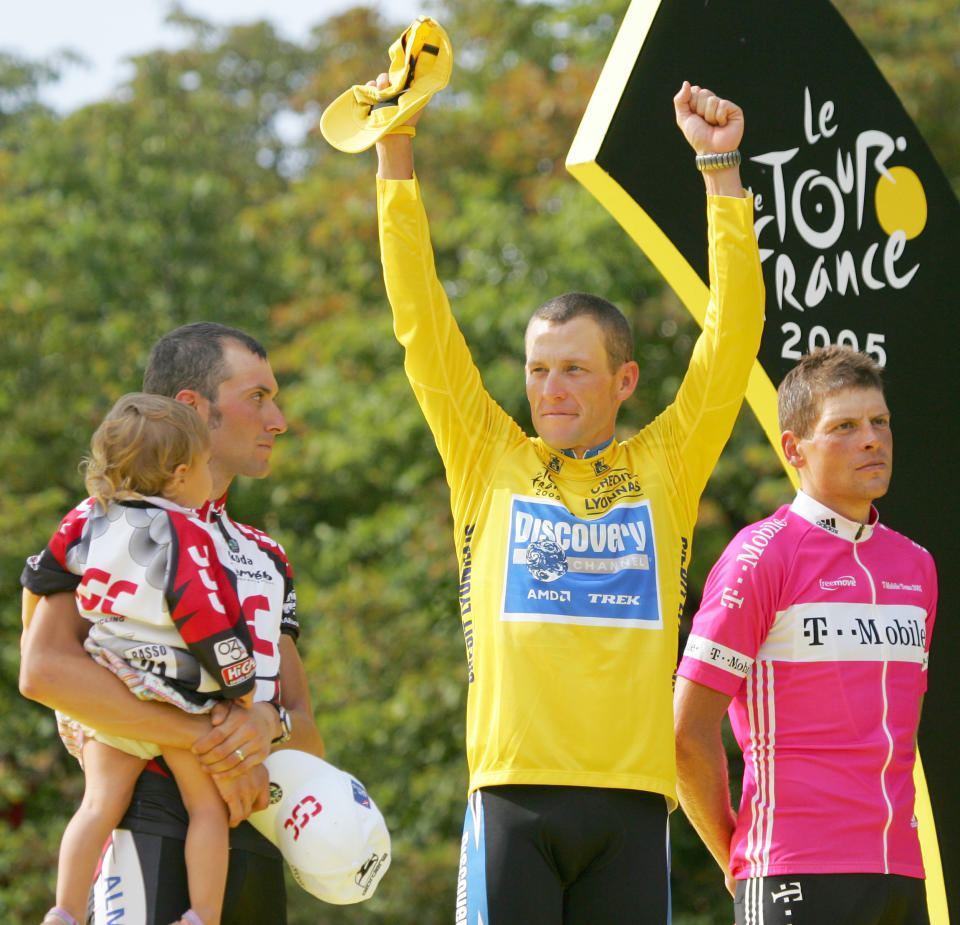 FILE - In this July 24, 2005 file photo, Lance Armstrong gestures from the podium after winning his seventh straight Tour de France cycling race, as second-placed Ivan Basso of Italy, left, and third-placed Jan Ullrich of Germany, look on, after the 21st and final stage of the race in Paris. Armstrong, he superstar cyclist whose stirring victories after his comeback from cancer helped him transcend sports, chose not to pursue arbitration in the drug case brought against him by the U.S. Anti-Doping Agency. That was his last option in his bitter fight with USADA and his decision set the stage for the titles to be stripped and his name to be all but wiped from the record books of the sport he once ruled. (AP Photo/Christophe Ena, File)