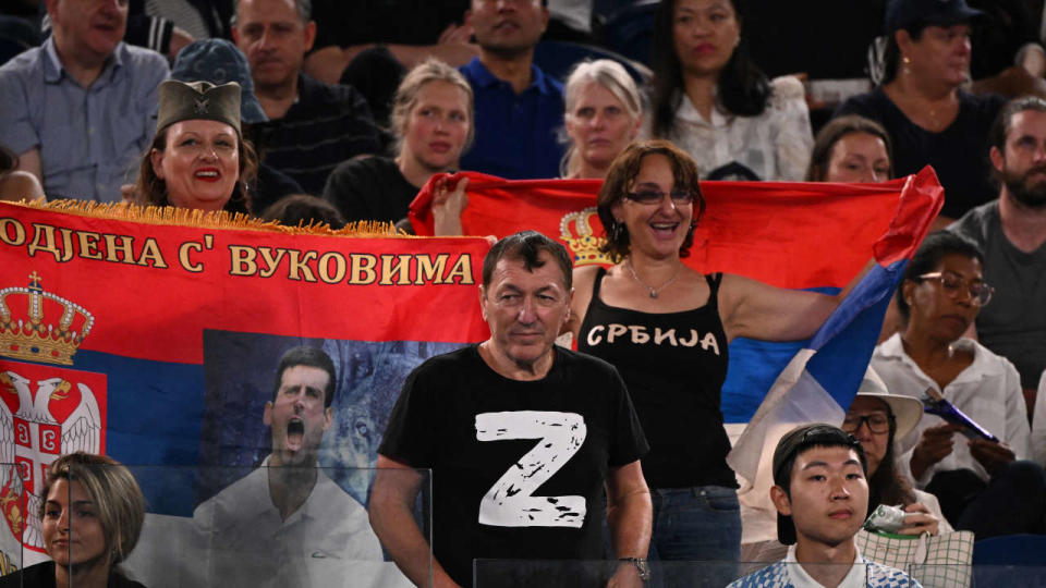 Un homme portant un t-shirt « Z » lors du quart de finale entre le Serbe Novak Djokovic et le Russe Andrey Rublev, à côté de supporters brandissant des drapeaux serbes, le 25 janvier 2023 à Melbourne.