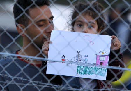 <p>A young girl holds up her drawing in a makeshift camp on the Greek-Macedonian border. (Ognen Teofilovski/Reuters)</p>
