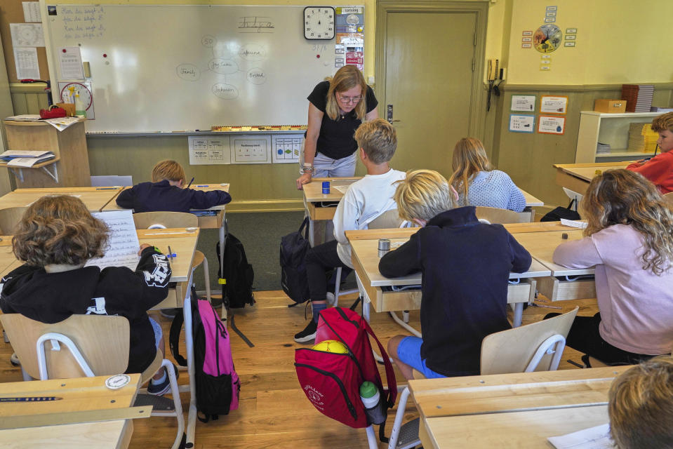 A teacher helps students practice their handwriting at the Djurgardsskolan elementary school in Stockholm, Sweden, Thursday, Aug. 31, 2023. As children across Sweden have recently flocked back to school after the summer vacation, many of their teachers are putting a new emphasis on printed books, quiet reading hours, and practicing handwriting as the country's yearslong focus on the digitalization of classrooms has come under scrutiny. (AP Photo/David Keyton)