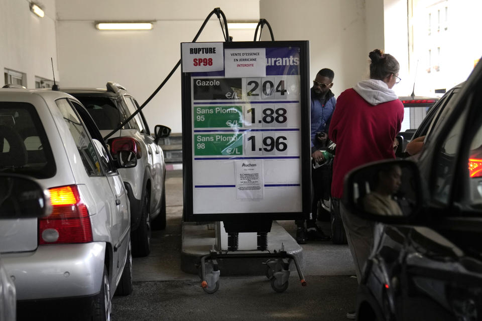 People fill up their tank at a gas station where placards read "No unleaded oil" and "Filling up jerry cans is forbidden", Wednesday, Oct. 12, 2022 in Cachan, outside Paris. The French government on Wednesday started the process of requisitioning workers at petrol depots of ExxonMobil's French branch Esso in an attempt to ensure that service stations around the country are supplied with badly needed fuel amid an ongoing strike, saying shortages are becoming "unbearable" to too many in the country.(AP Photo/Francois Mori)